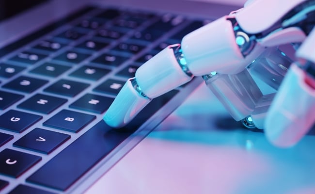 A robotic hand touches keys on a computer keyboard