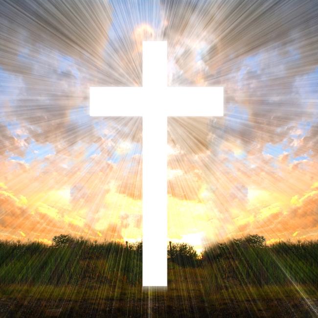 A white cross, lit by sunlight, against a pink and blue sky.