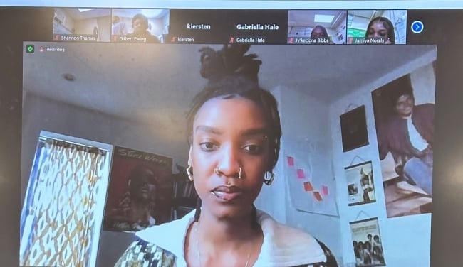 A Zoom screen shows Spelman College teaching fellow Tangela Mitchell, a brown-skinned woman with a nose ring and her hair styled on top of her head, in the center and six high school students taking part in a discussion section.
