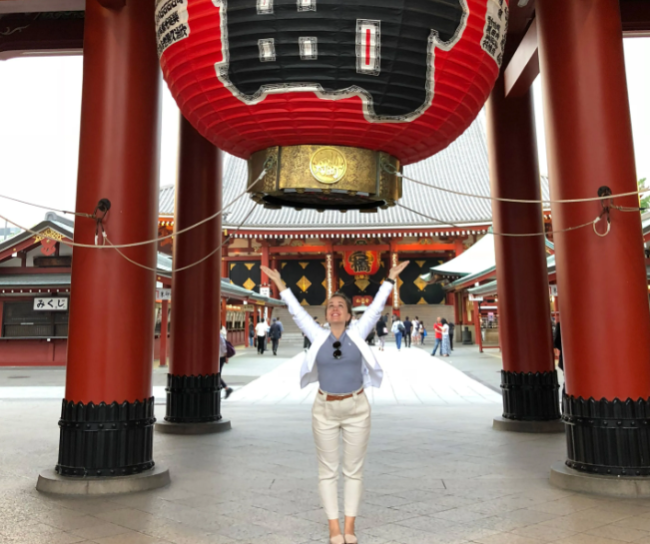 Leeza Fernand, an administrator at Northern Virginia community college, stands below a large, red lantern with her arms outstretched.