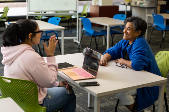 Mayra Lopez-Perez works with a student at a table.