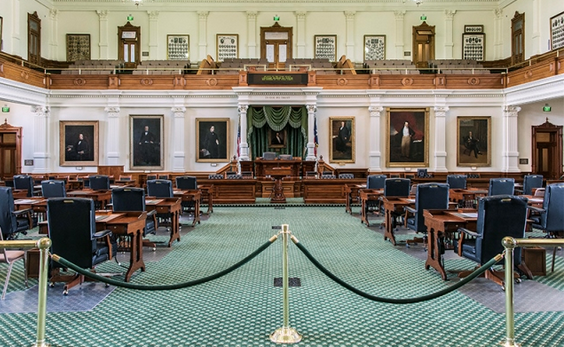 The Texas Senate chamber, with an aqua-blue rug and wooden desks and chair.