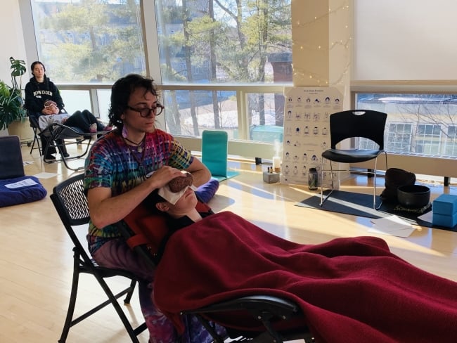 Two students receive Reiki at Bowdoin college.