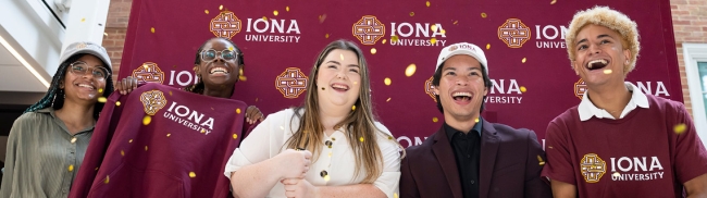 Five students in Iona gear smile in front of a burgundy Iona backdrop.