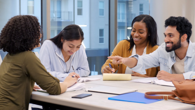 A group of students sits in a study room working together.