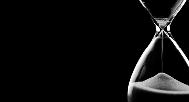 An image of an hourglass against a black background. 