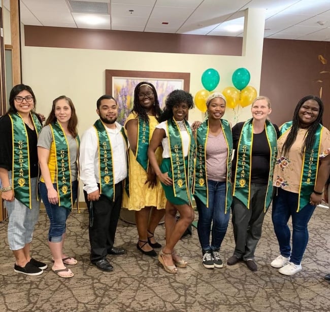 A group of graduates wearing green satin stoles denoting their participation in the Guardian Scholars Program.