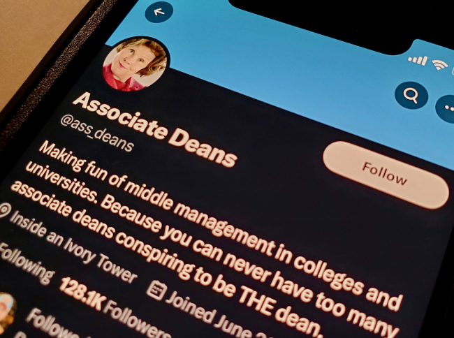 A phone displaying the Associate Deans Twitter account, with a photo of Imelda Staunton as Dolores Umbridge in the profile photo spot.