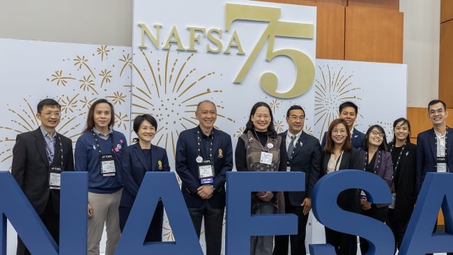 A group of people stands in front of a sign that says "NAFSA 75"