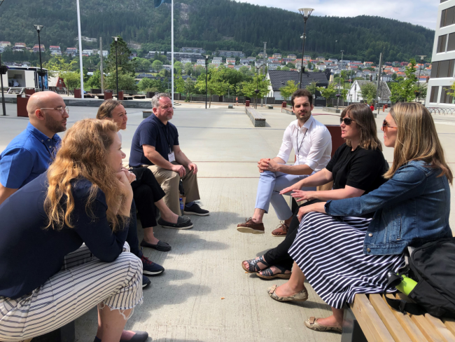 Babson and Nord leaders sit talking on wooden benches on a sunny day in Norway.