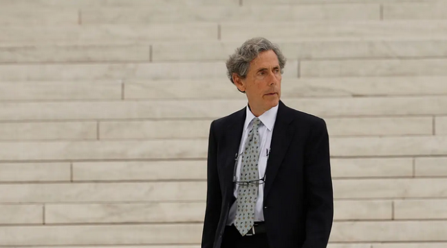 Edward Blum, a middle-aged light-skinned man with gray hair wearing a suit and standing on marble steps.