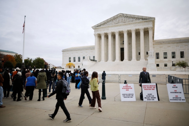 The scene in front of the Supreme Court Oct. 31, when the court heard arguments in two cases challenging race-conscious admissions in higher education: a lone opponent of affirmative action, with protest signs, stands next to a group of mostly young people rallying in support of affirmative action.