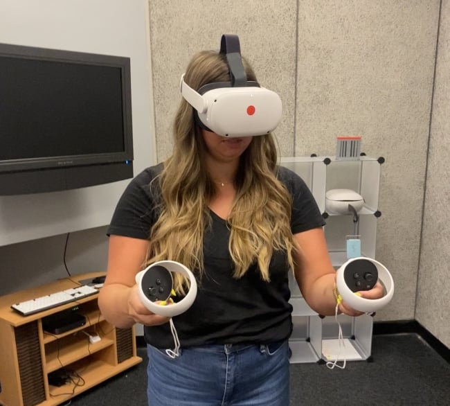 A student uses IUPUI's VR headset and joysticks to practice public speaking.