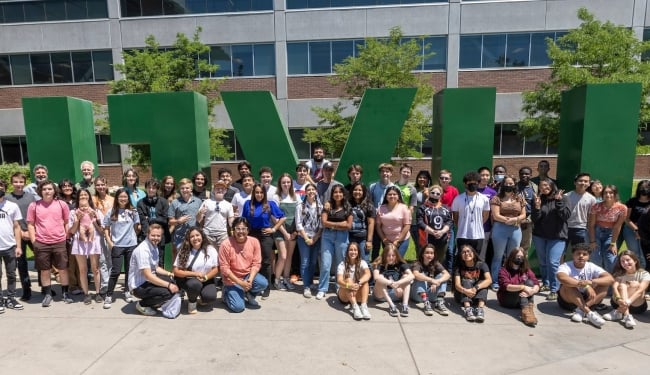 A crowd of students in front of a sculpture that spells UVU