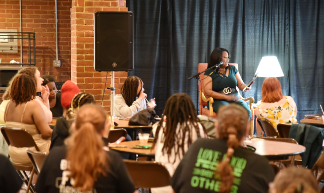 Students face President Mary Dana Hinton on stage in the Hollins University Rathskellar.