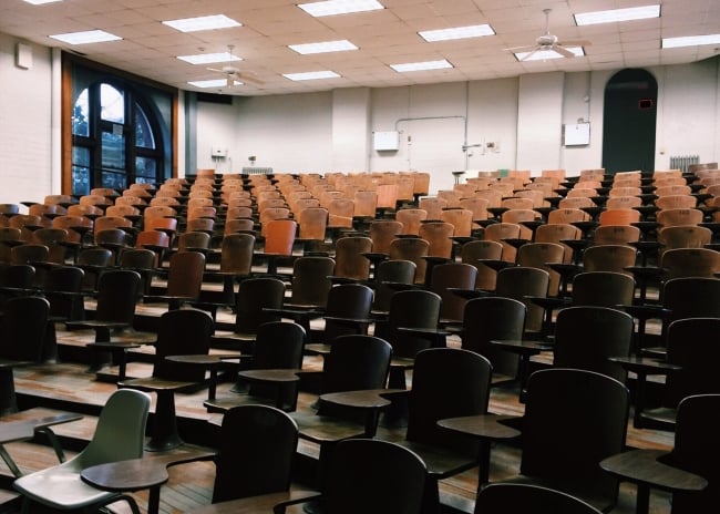 An empty lecture hall full of brown chairs.