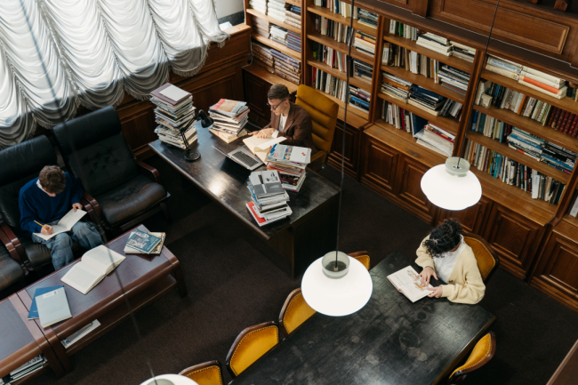 Three students study independently in a library.