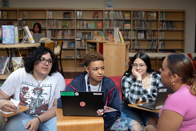 Four people sit around a computer