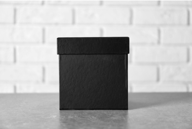 A black box on a table against the background of a white wall.