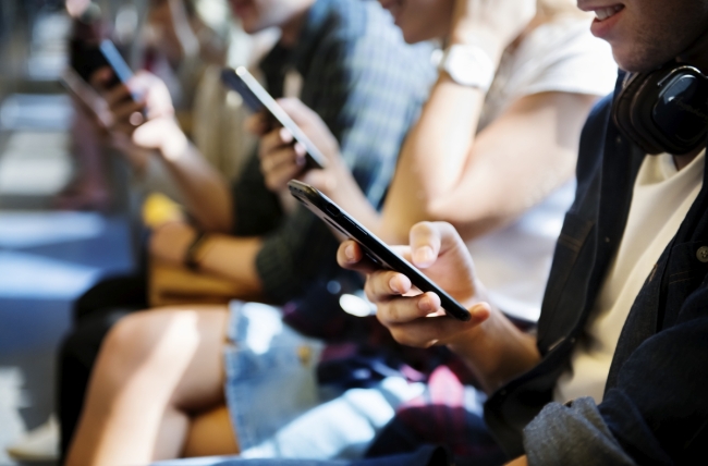 A group of young adults looking at their smartphones.