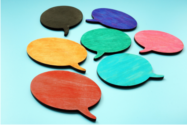 A cluster of seven brightly colored speech bubbles, in seven different colors, against a sky-blue background.