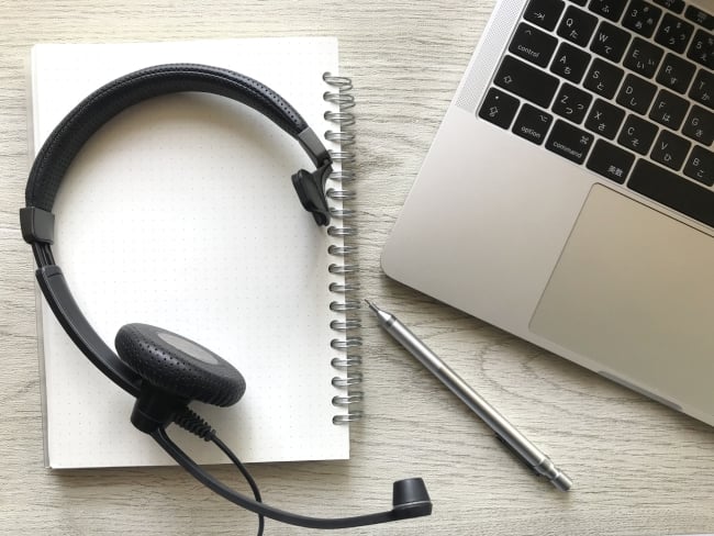 Photo of a computer, headset and pad with pen