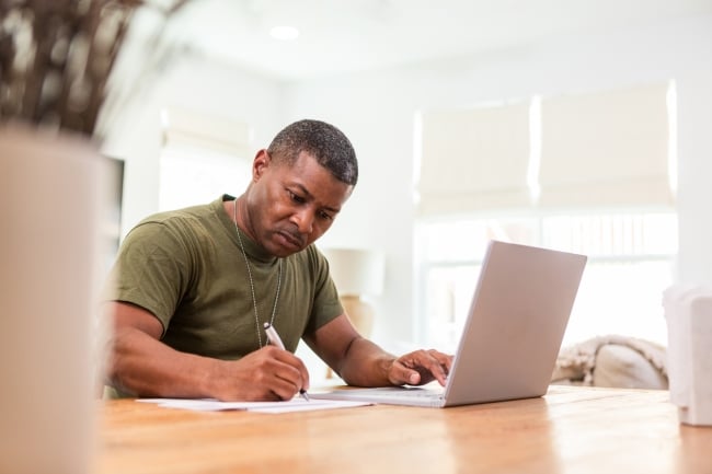 A mature veteran works at a computer on a table.