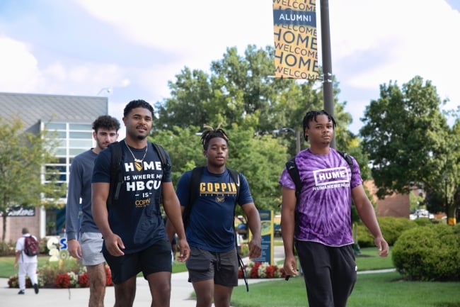 Four students, some in Coppin State University T-shirts, walk on campus. 