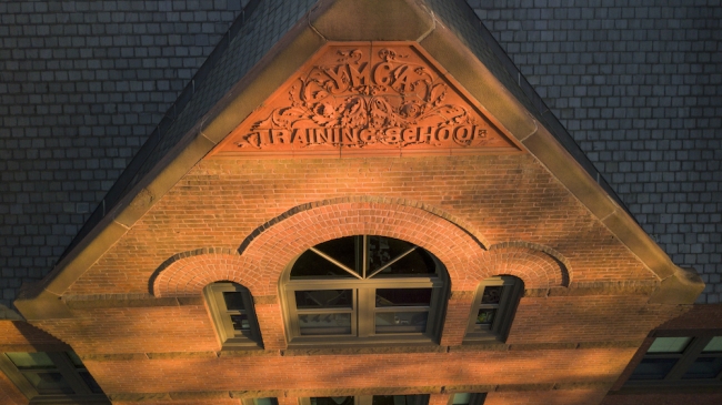 A high-angle shot of a brick building engraved with the words "YMCA Training School."