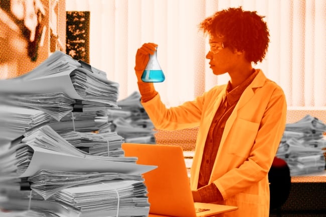 A woman in a lab coat looking at a beaker of blue liquid, surrounded by piles of documents