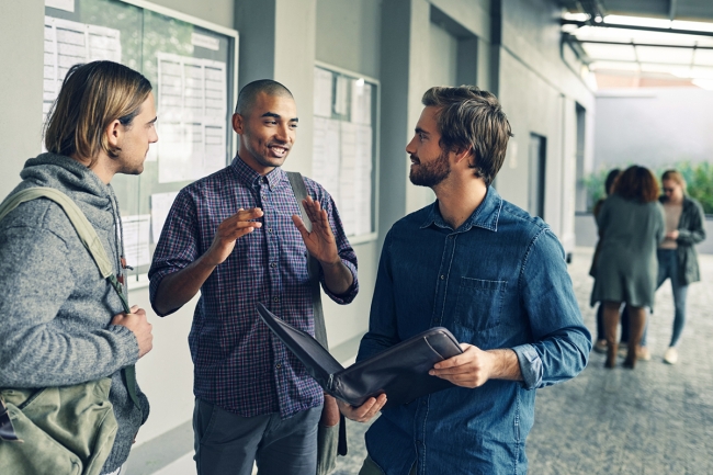 Adult learners stand in a hallway talking to one another