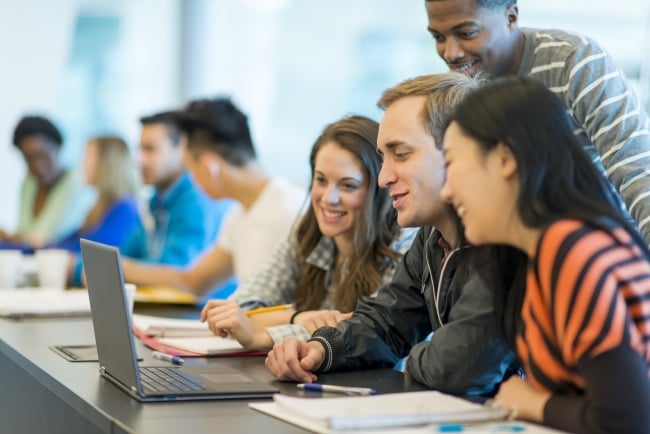 A group of college students works together on a laptop