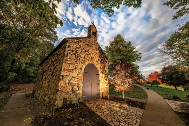 A stone building with a wooden door topped by a cross on Franciscan University of Steubenville's campus. 