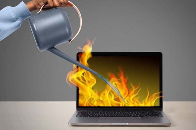 A watering can pouring water onto a laptop that is on fire.