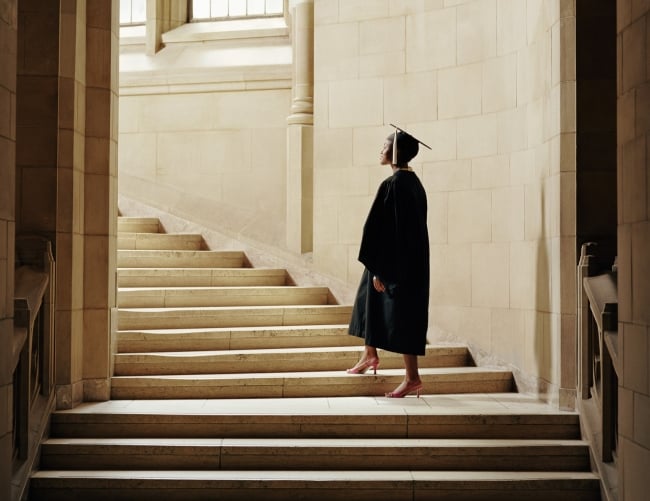 A woman in a cap and gown going up the stairs