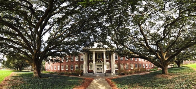 A columned brick campus hall surrounded by trees
