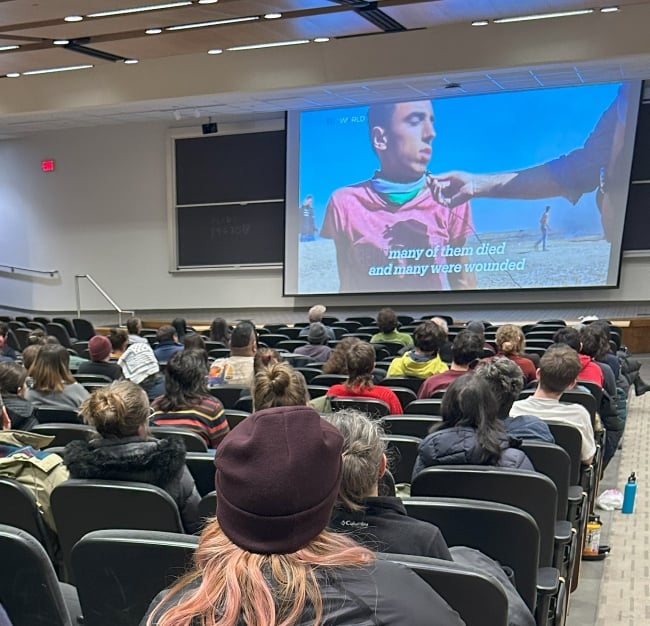 An auditorium of students watching a film