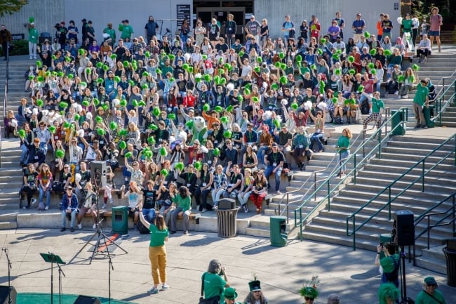 A crowd of students in bleachers wearing green