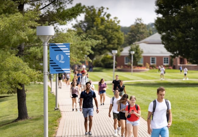 Students walk on Quinnipiac University's campus on a sunny day.
