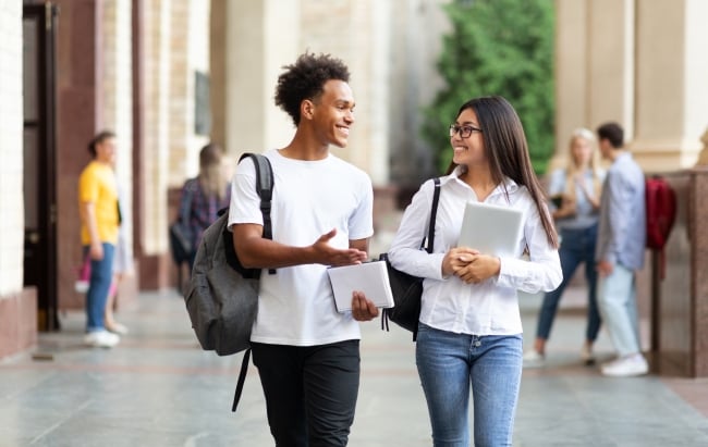 College friends walking on campus and talking, having break after classes.