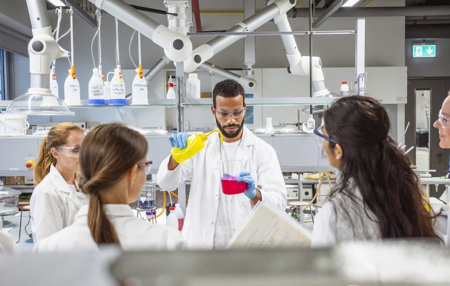 Five scientists conduct an experiment in a science lab