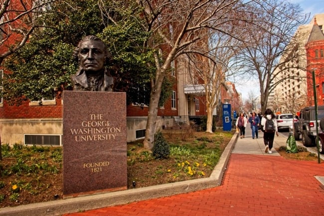 A college campus with a bust of George Washington outside
