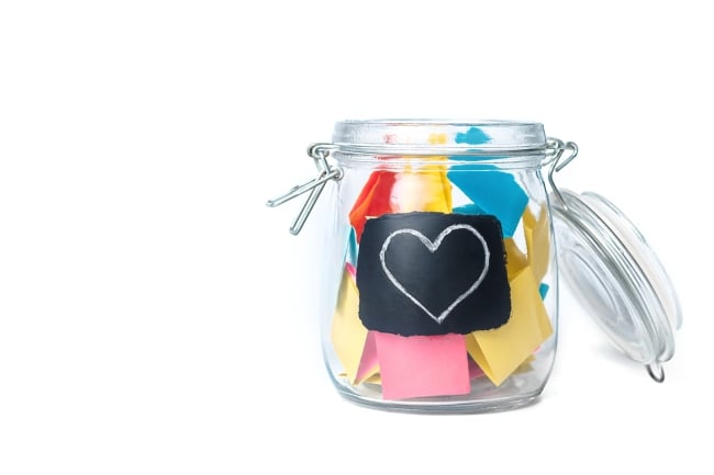 Clear jar with a heart on the front full of variously colored sticky notes 