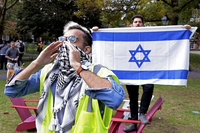 Pro-Palestine protester at Harvard stands in front of man holding Israeli flag