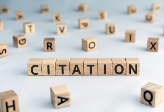The word "citation" is spelled out using wooden blocks. Other blocks featuring various letters of the alphabet are strewn around.