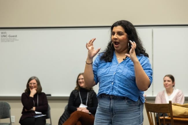 A student wearing blue shirt and jeans shows surprise during a performance of a play to raise awareness about mental health.
