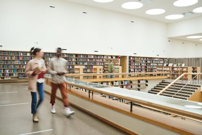 Blurred motion of people walking along the corridor in big library