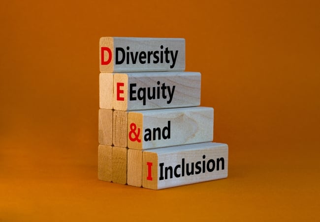 A stack of four wooden blocks with the words “Diversity, Equity and Inclusion” against an orange background.