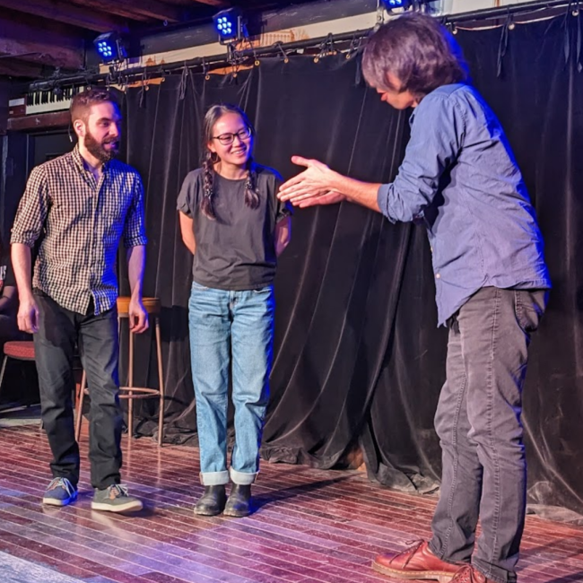 Three students play an improv game on stage.