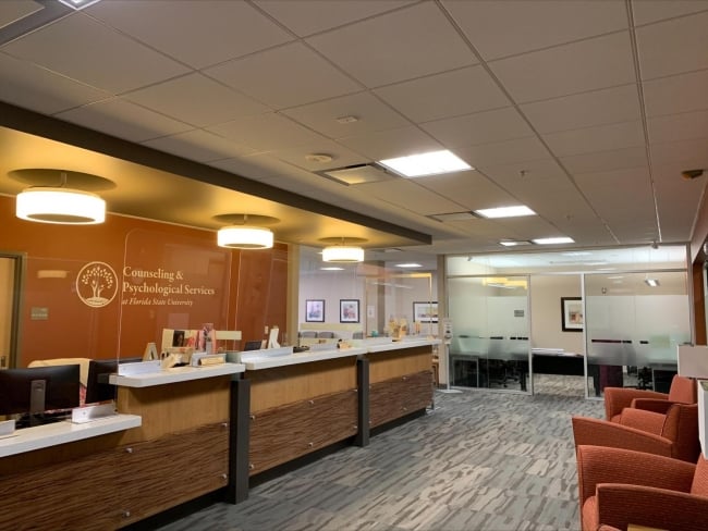 A photo of a lobby with multiple chairs and a long counter. The wall reads: "Counseling and Psychological Services, Florida State University."